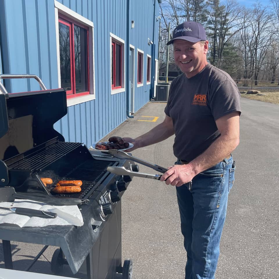 An MRR team member grilling outdoors during a company gathering, from the timeline