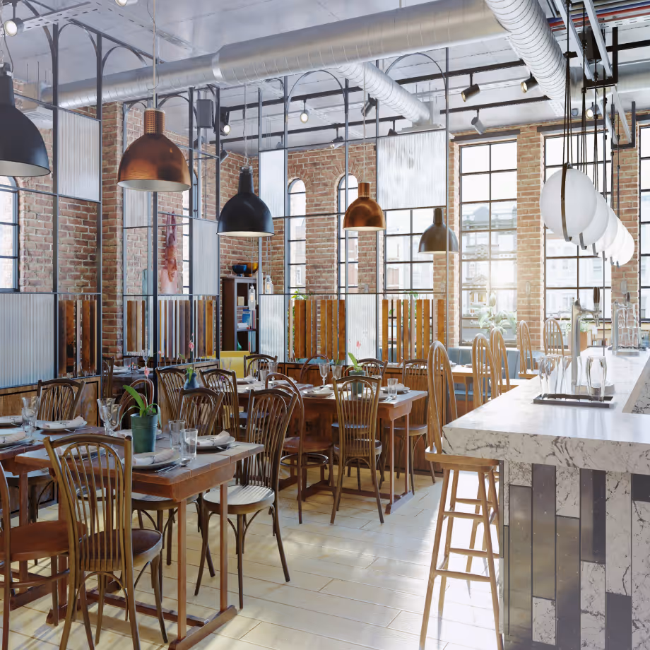 Bright cafe interior with wooden tables, chairs, large windows, and industrial-style hanging lamps.