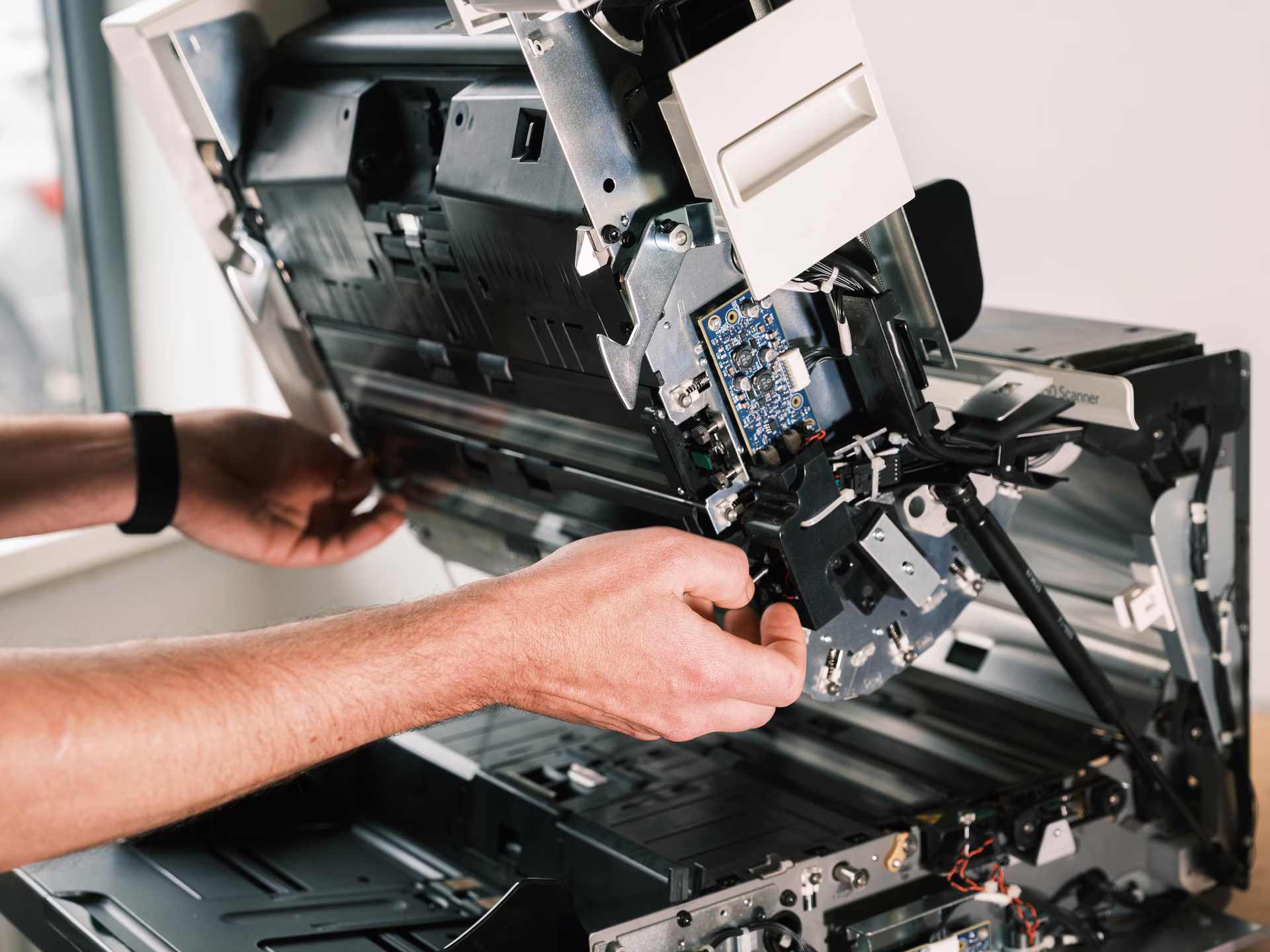 Engineer adjusting a circuit board inside an opened document scanner