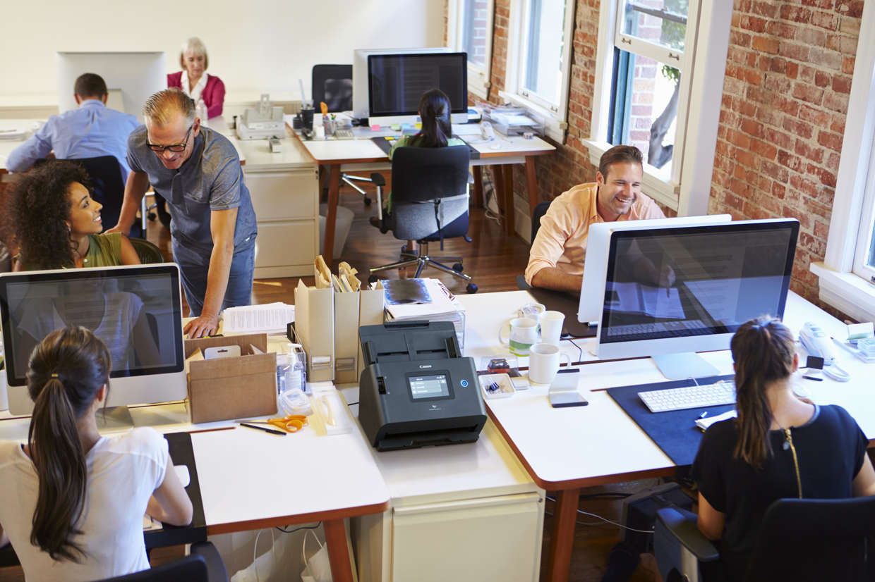Canon network document scanner on a desk in a shared open-plan office
