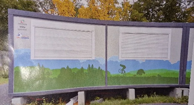 Mur peint avec paysage vert et cycliste en silhouette, entouré d'arbres jaunes et verts.