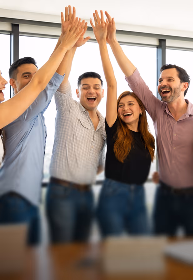 Gruppe von lächelnden jungen Erwachsenen im Büro geben sich freudig die Hände zum High-Five.