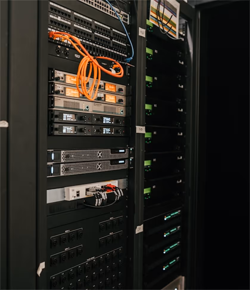 Serverschrank mit vernetzten Netzwerkgeräten und orangefarbenen Kabeln in einem Serverraum.