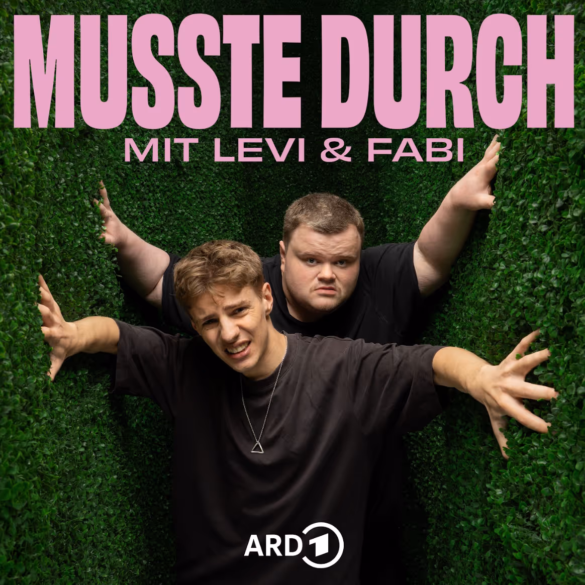Zwei Männer drücken sich in einem engen grünen Heckenlabyrinth zusammen, Titel MUSSTE DURCH.