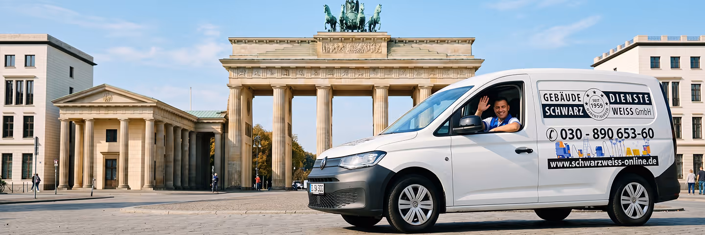 Mann winkt aus weißem Firmenwagen vor Brandenburger Tor in Berlin bei klarem Himmel.