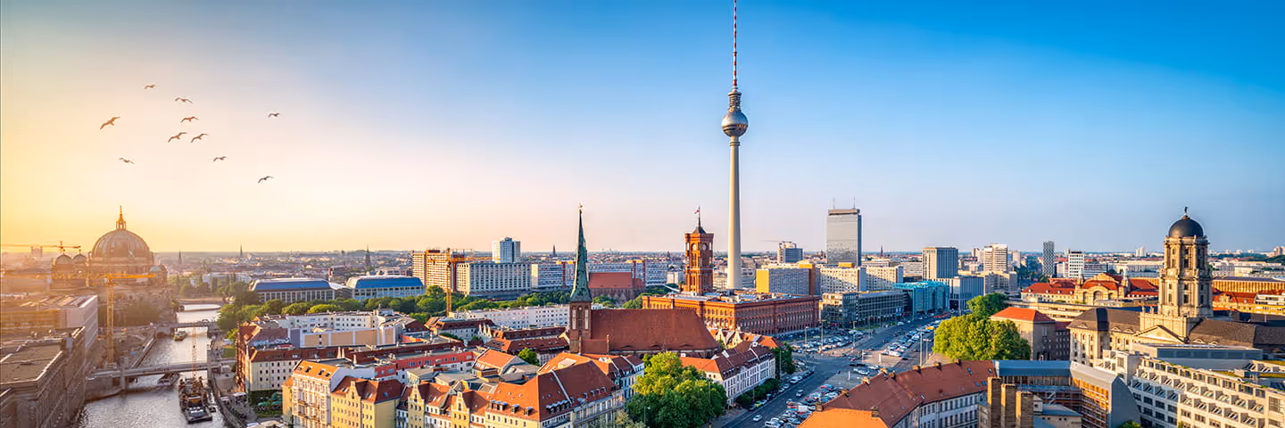 Panoramablick auf Berlin bei Sonnenuntergang mit Fernsehturm, Dom und Stadtsilhouette.