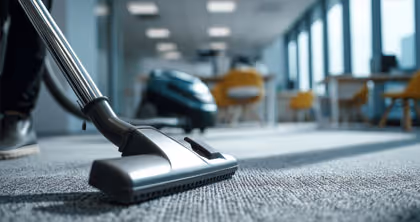 Staubsauger auf einem Teppich in einem modern eingerichteten Büro mit Stühlen und Tischen.