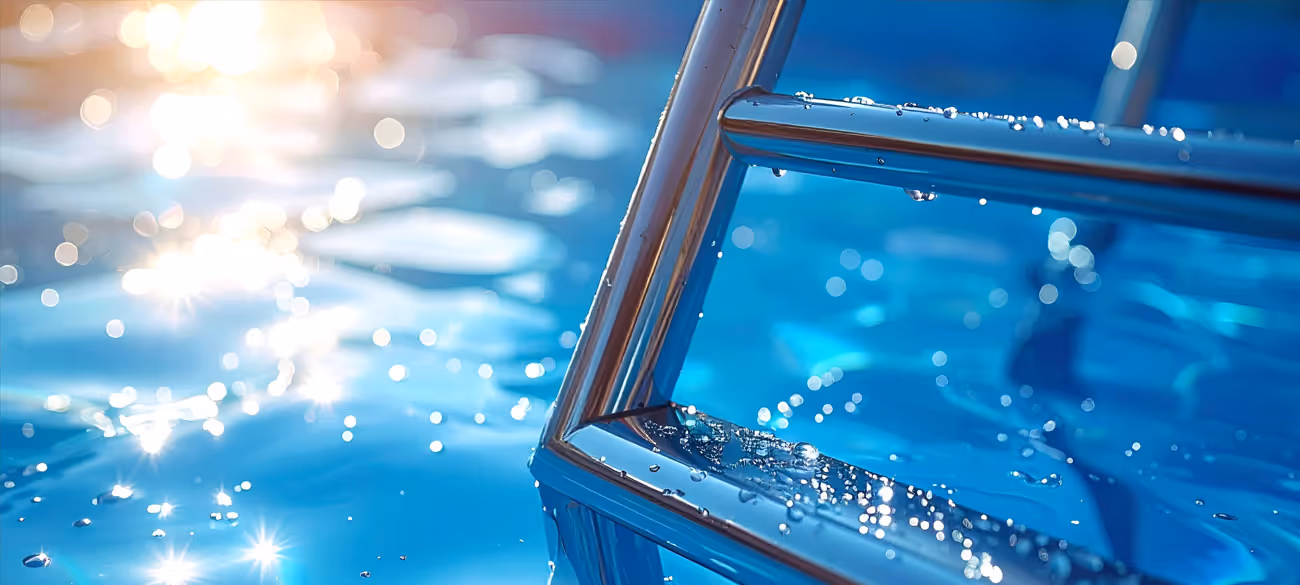 Sonnenlicht spiegelt auf klarem blauen Wasser an einer nassen Metallleiter im Schwimmbad.