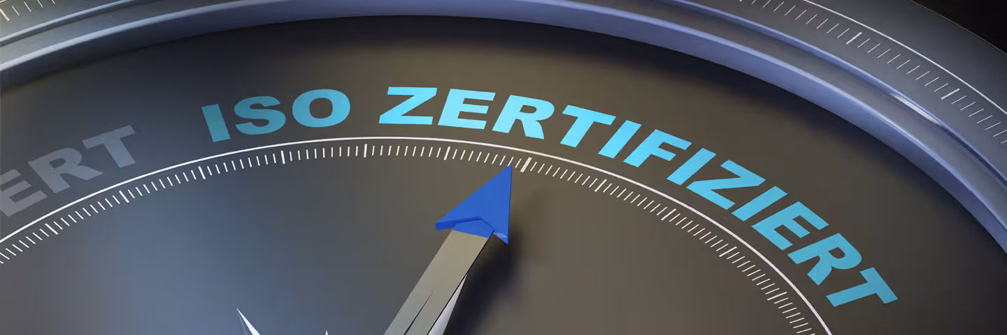 Kompassnadel zeigt auf den Schriftzug ISO Zertifiziert auf einem schwarzen Zifferblatt.