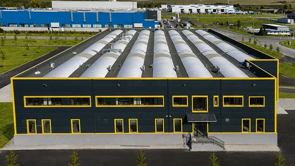 Industrial building with a dark blue facade, yellow window frames, and a curved roof.