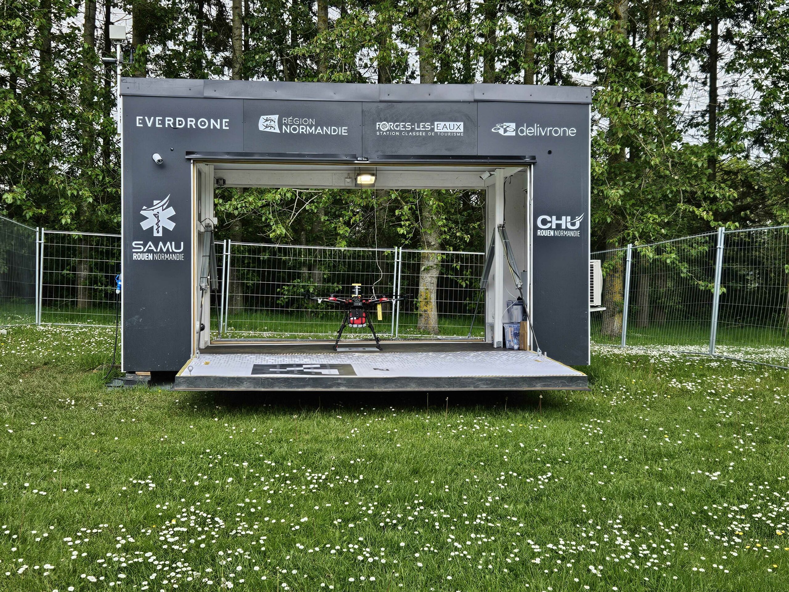 A drone hangar with logos for Everdrone, Région Normandie, Forges-les-Eaux, Delivrone and CHU Rouen Normandie