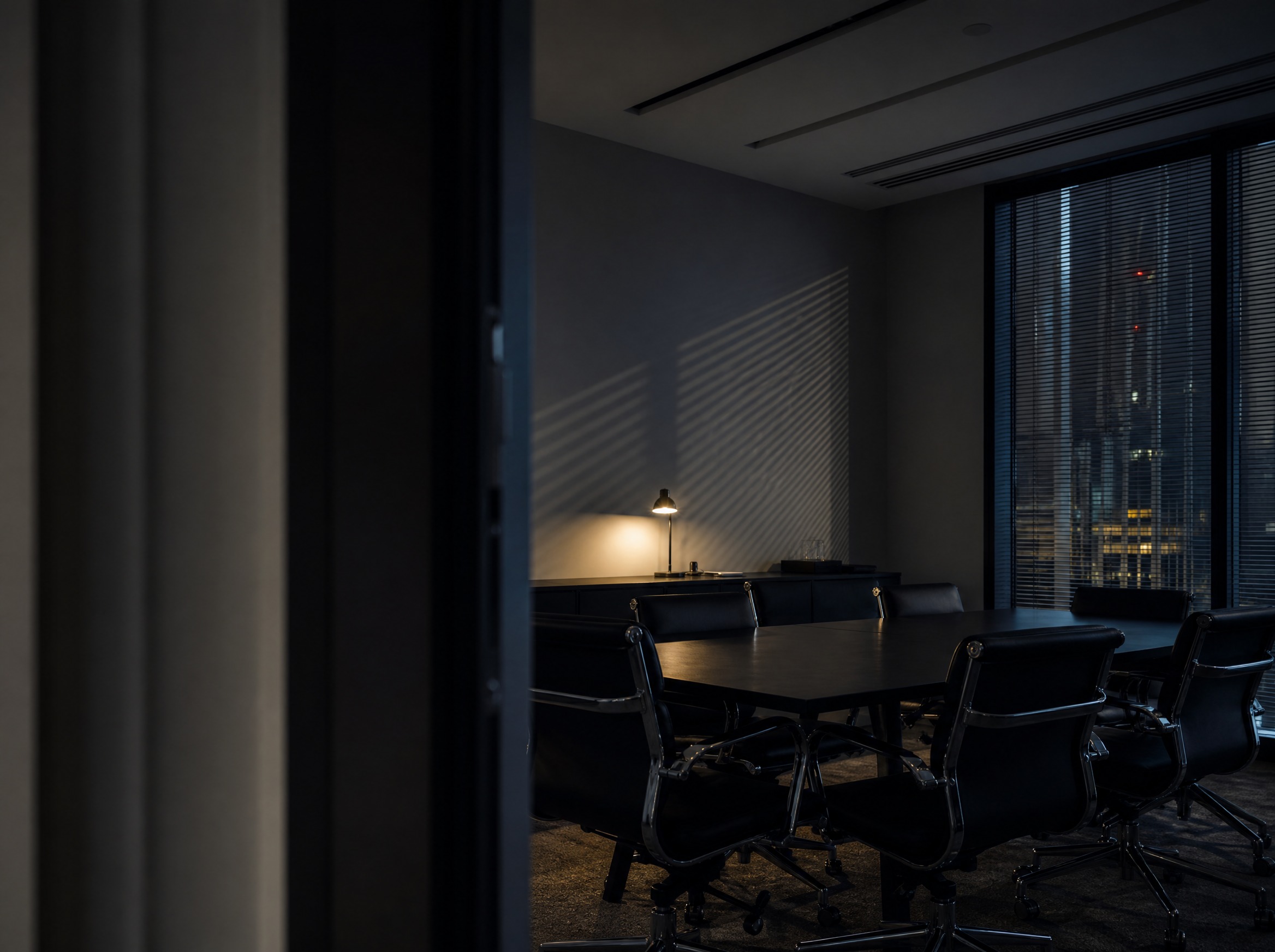 An empty meeting room at dusk with a long table and the city beyond the window