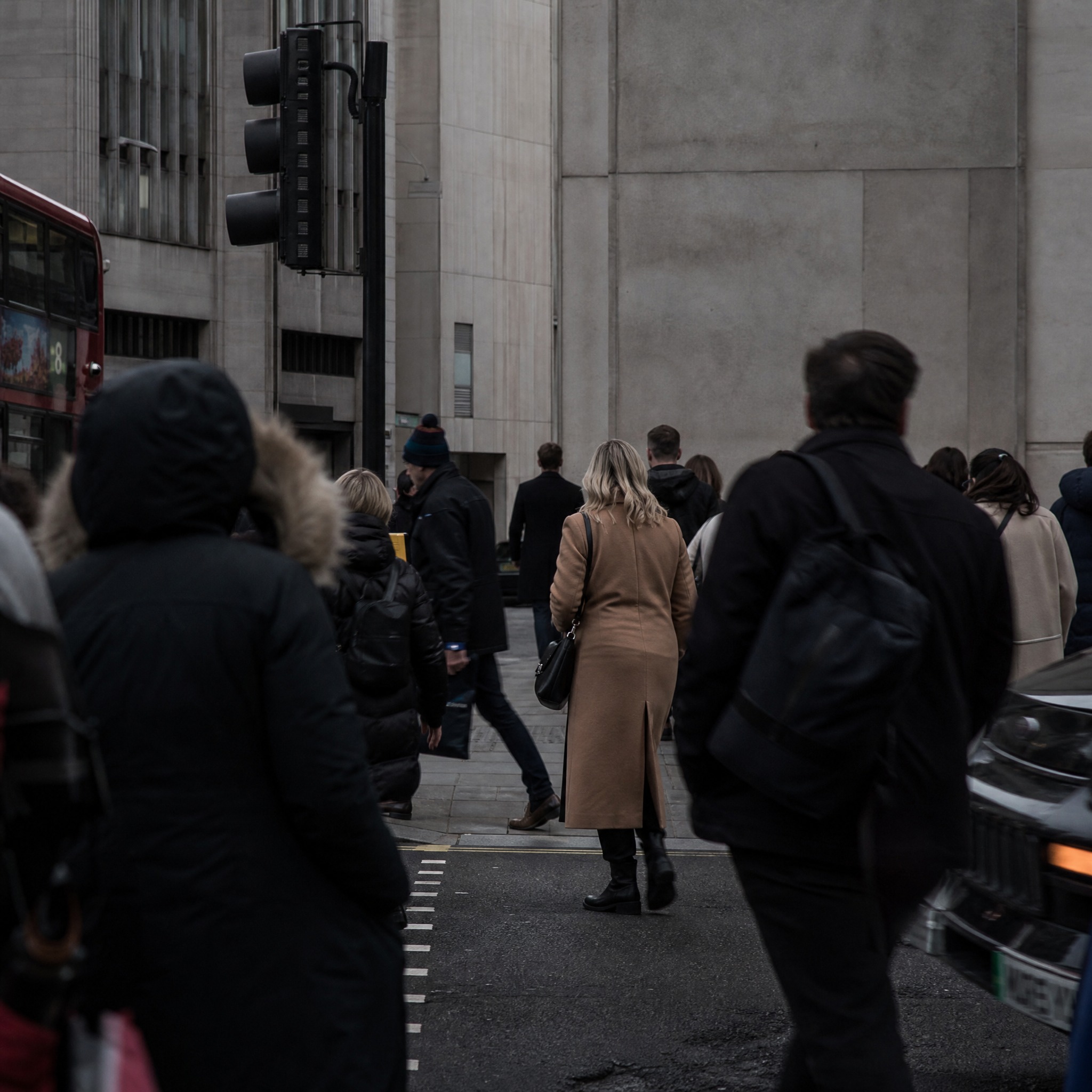 A crowd of pedestrians seen from behind crossing a city street