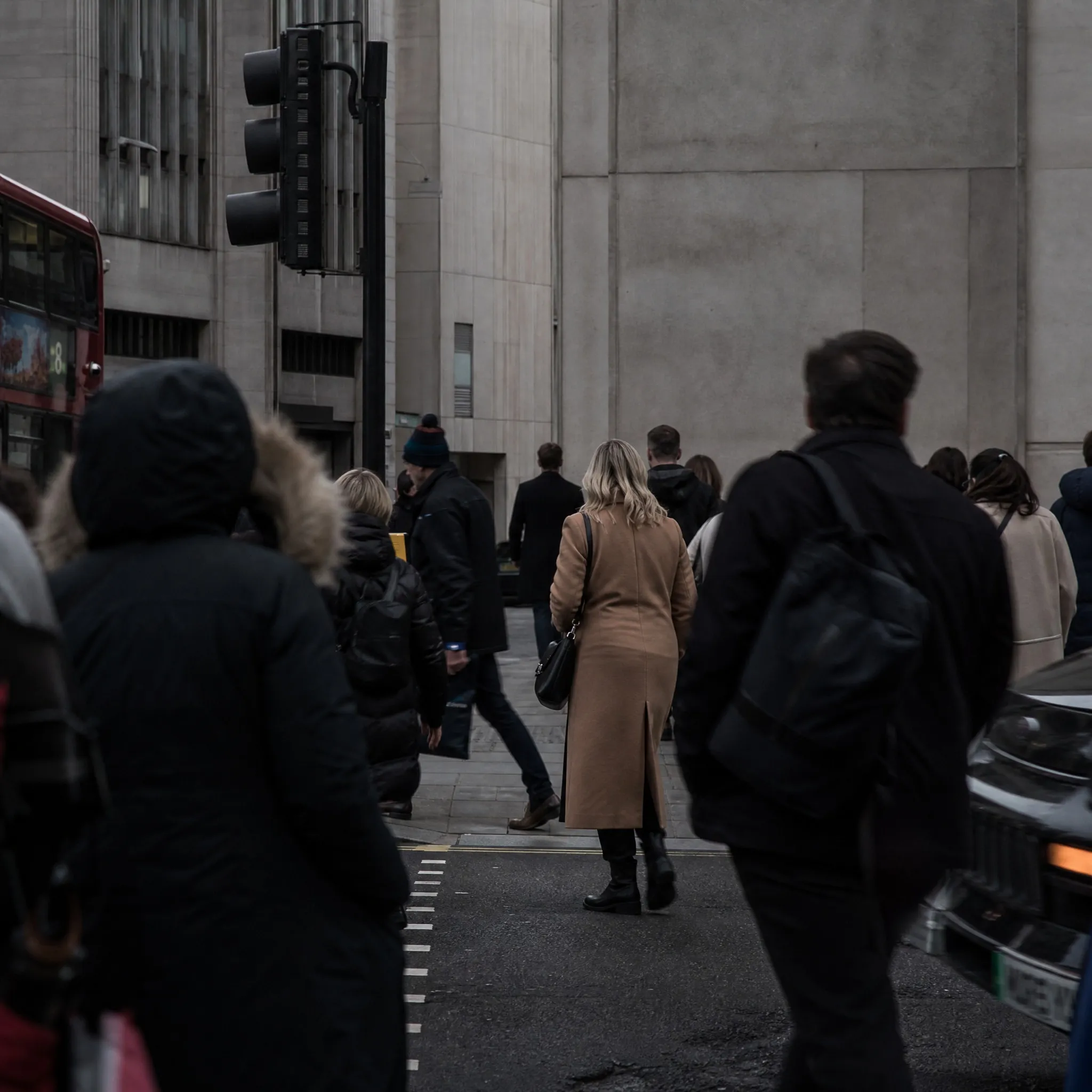A crowd of pedestrians seen from behind crossing a city street