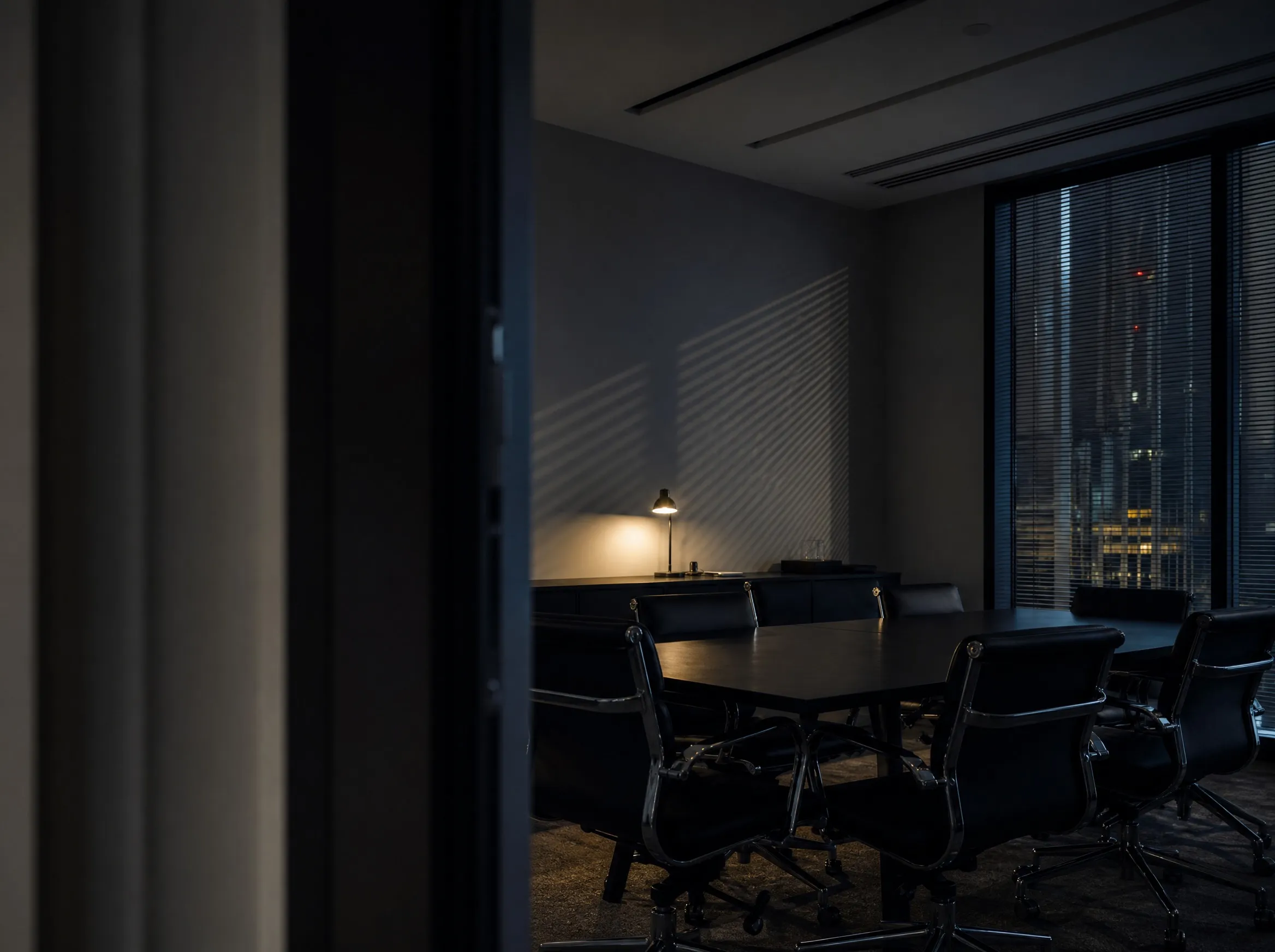 An empty meeting room at dusk with a long table and the city beyond the window