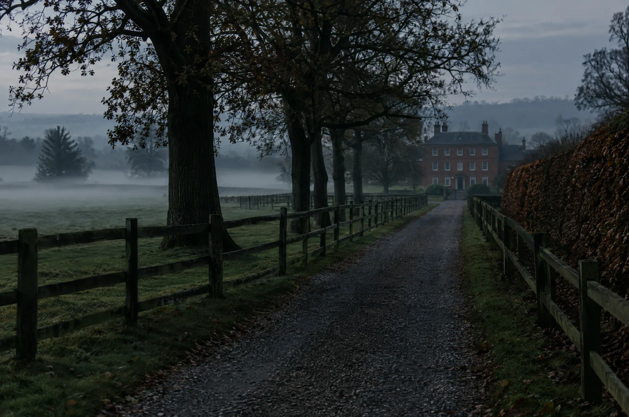 A gravel drive through misty Hertfordshire paddocks towards a distant red brick house