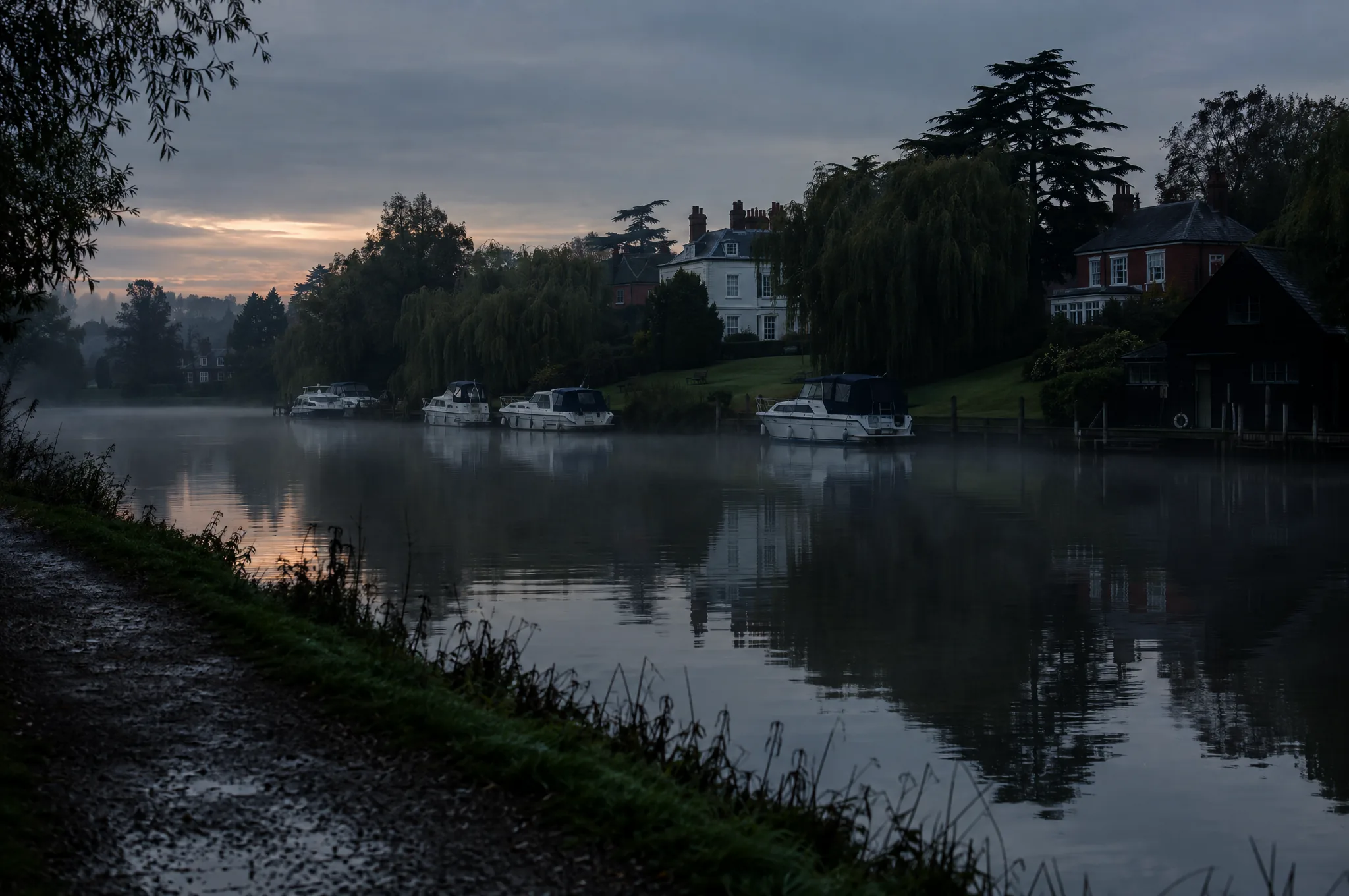 Large riverside houses and moored boats on the Thames at Walton in early morning mist