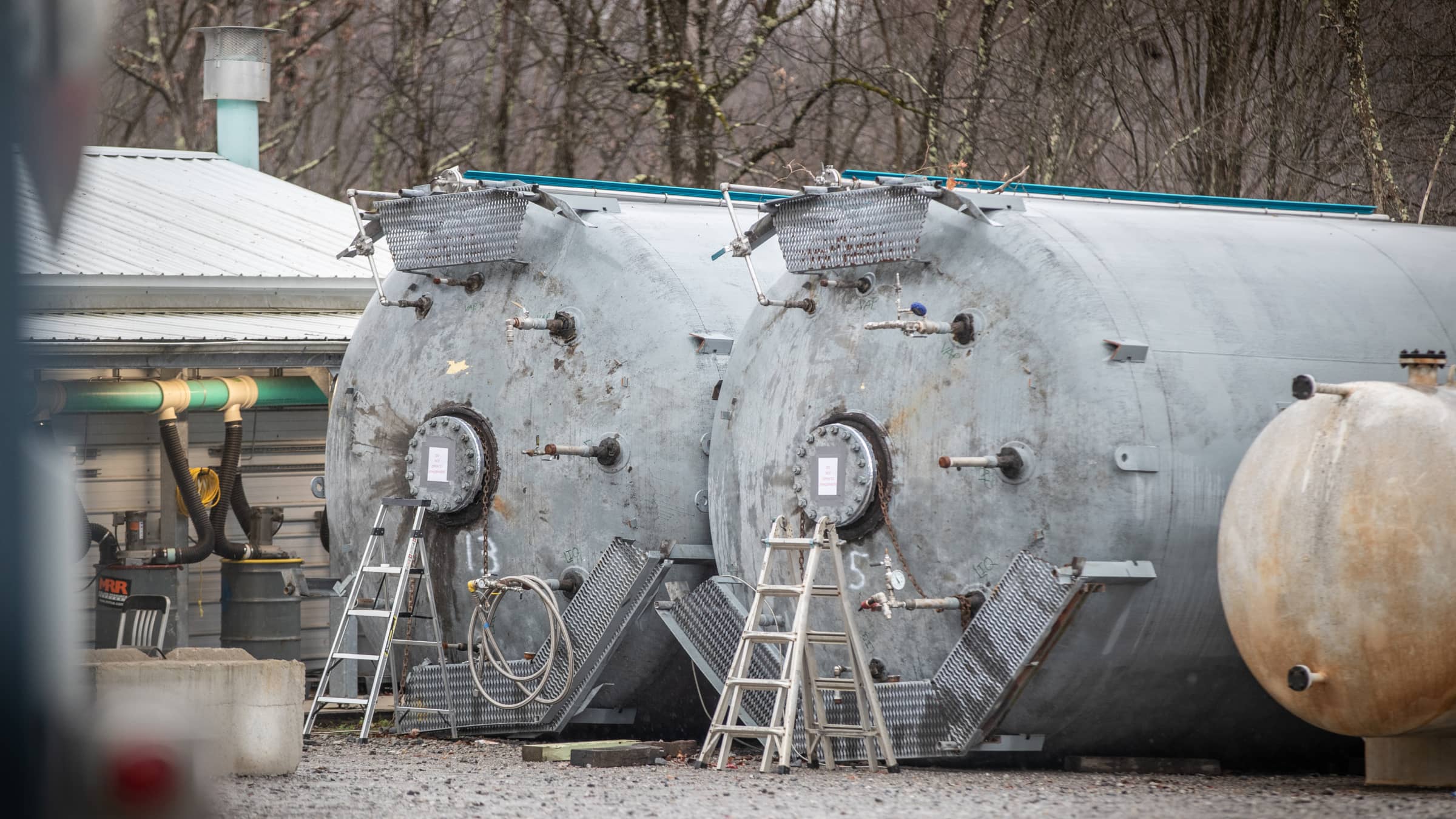 Two gray decomission tanks in a yard