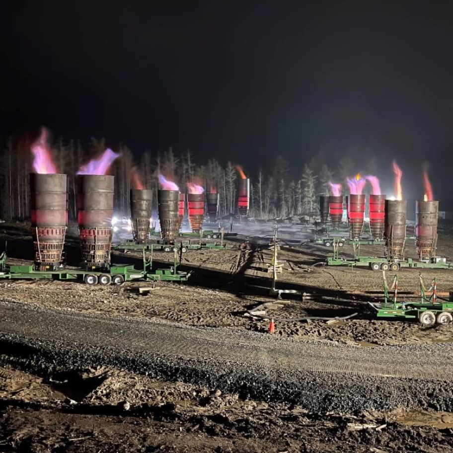 Row of portable flare units operating at night to generate flow for an inline pipeline inspection campaign in northern Ontario