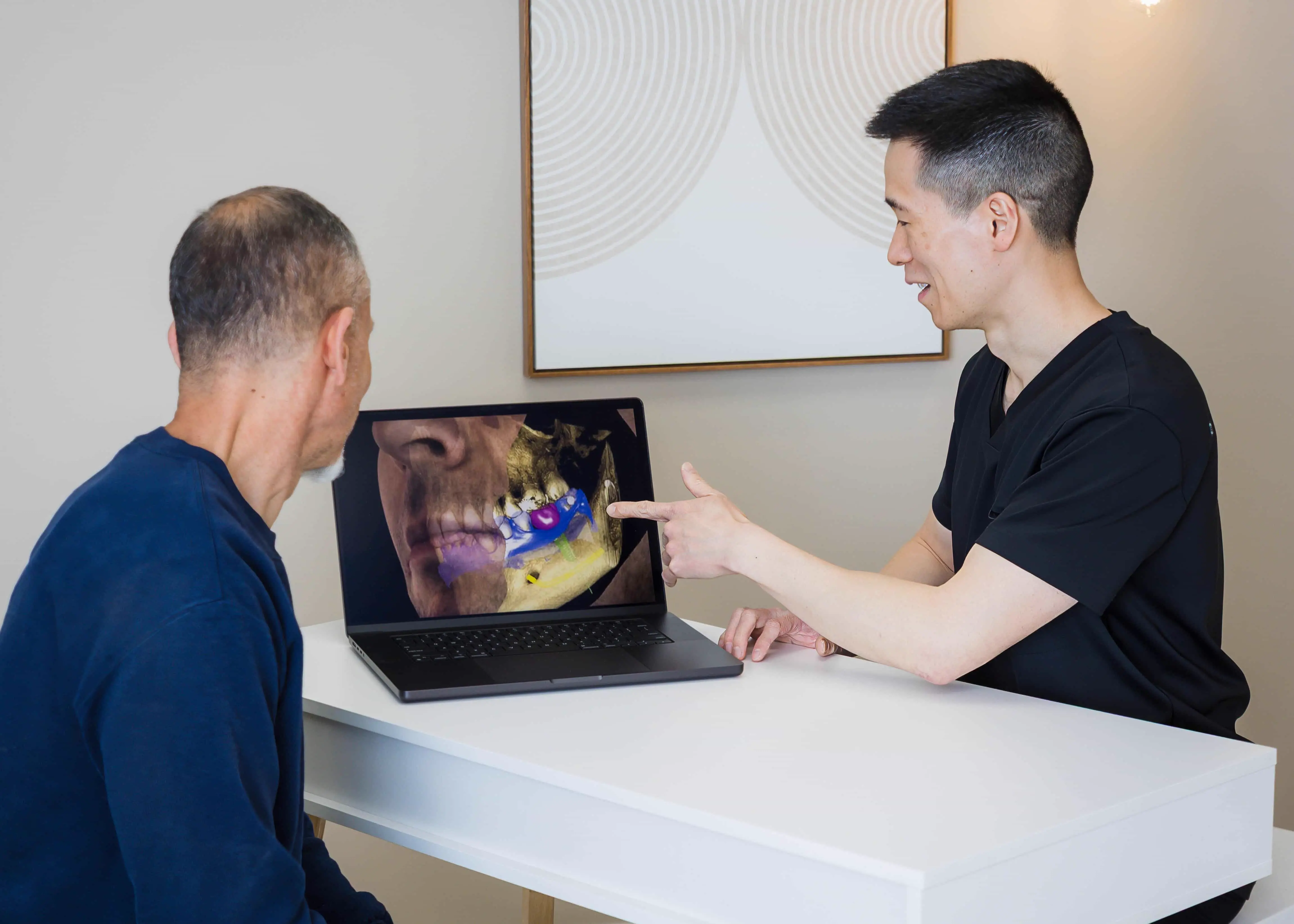 Dr. Chou and patient reviewing dental treatment plan on computer screen