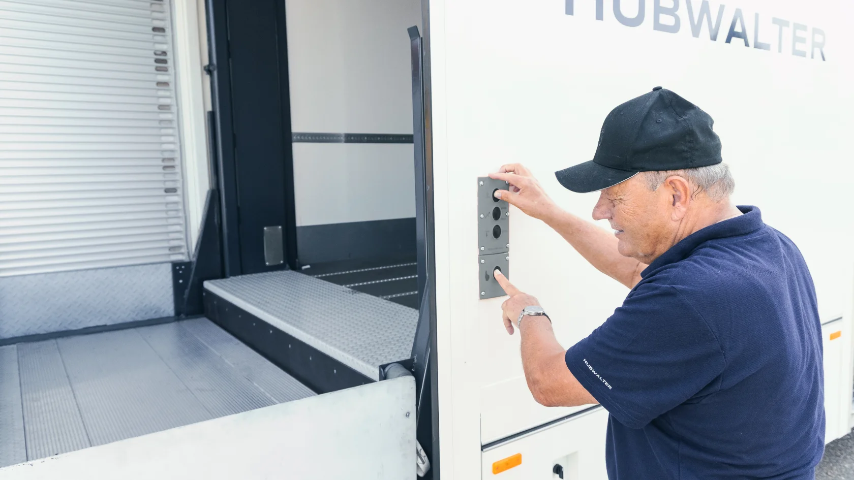 Lieferfahrer lädt Pakete in einen weißen Hubwalter LKW mit Ladeklappe in einer engen Lieferzone.