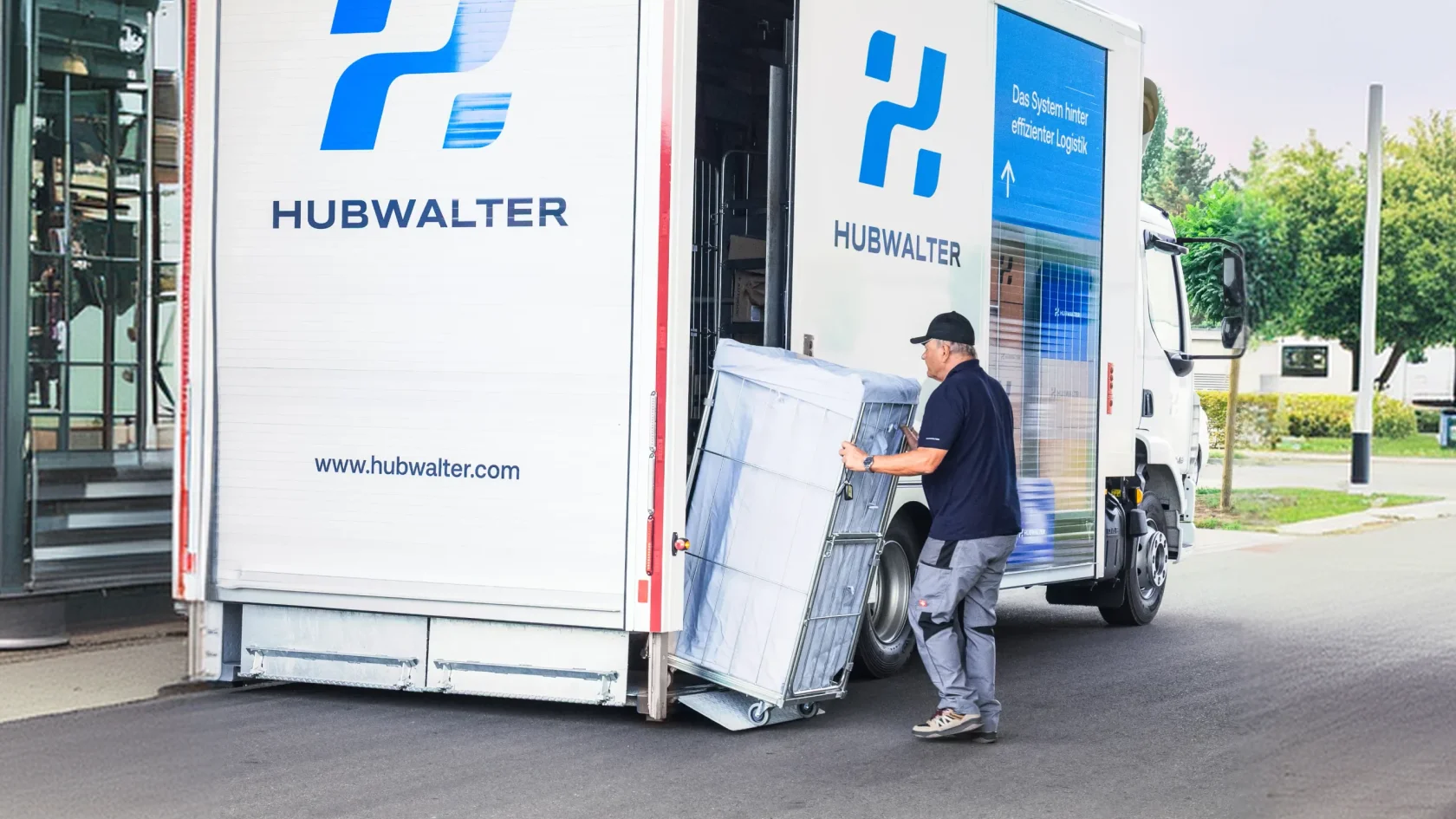 Mitarbeiter lädt Waren auf einen Wagen aus einem Hubwalter Kofferaufbau im Hinterhof.