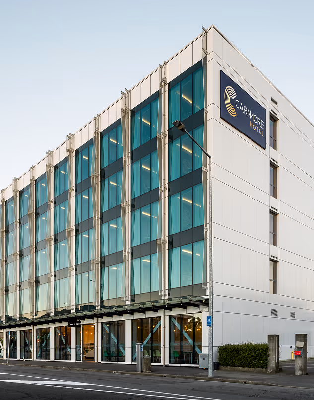 Modern multi-story building with large glass windows and a Carmore Hotel sign on the corner.
