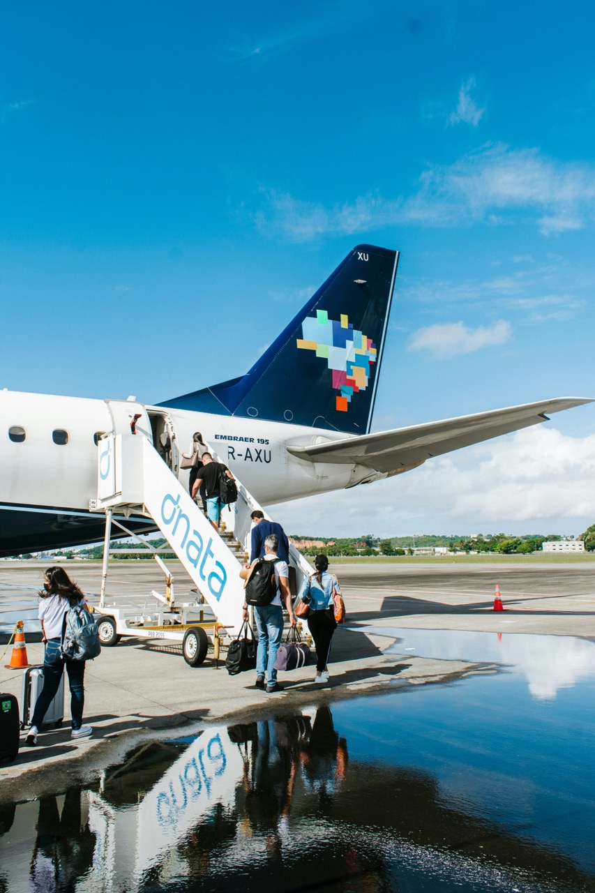 Passengers boarding an Embraer 195 commercial aircraft from an airport tarmac