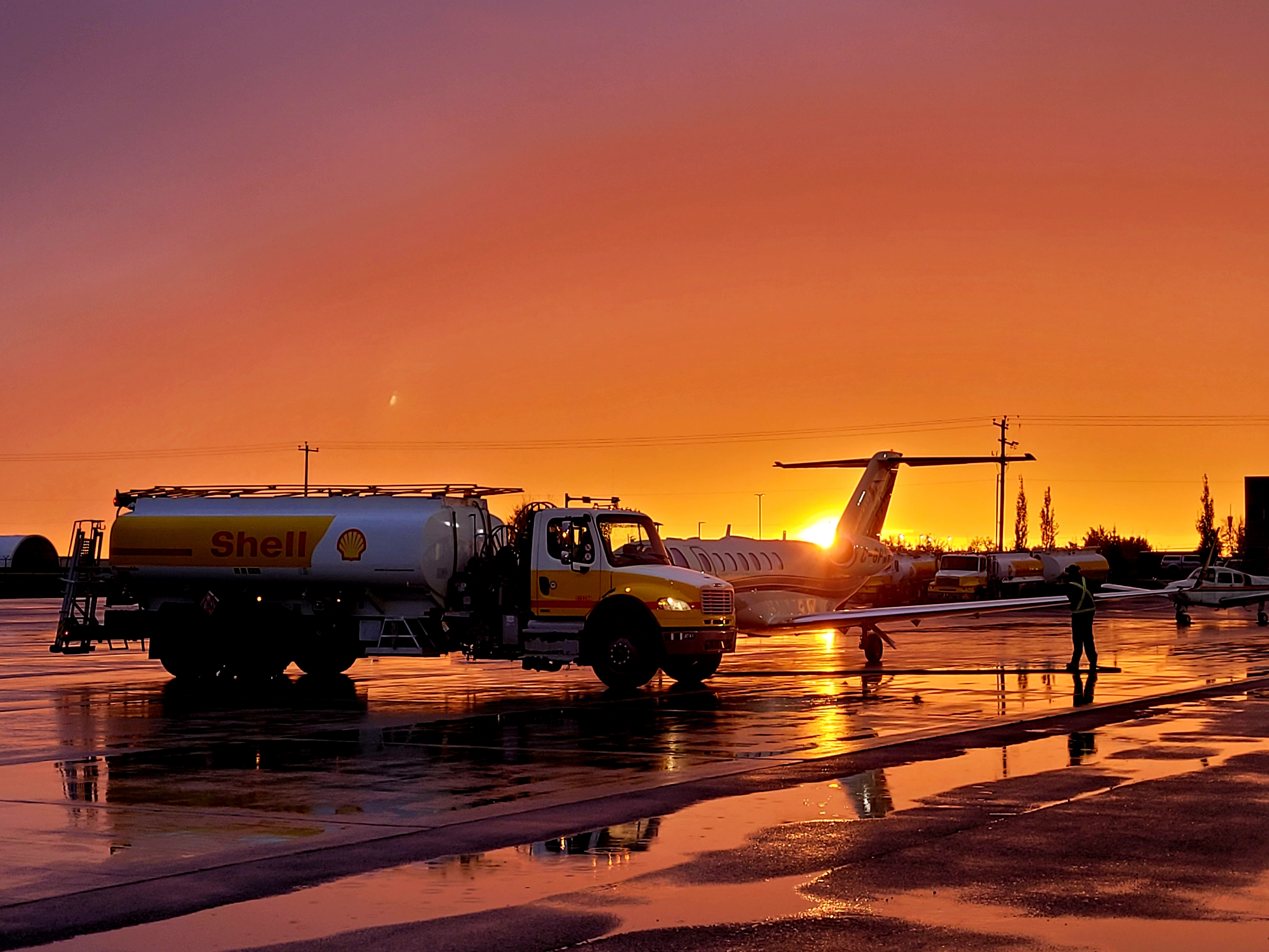 Shell aviation fuel truck refuelling a private jet at sunset