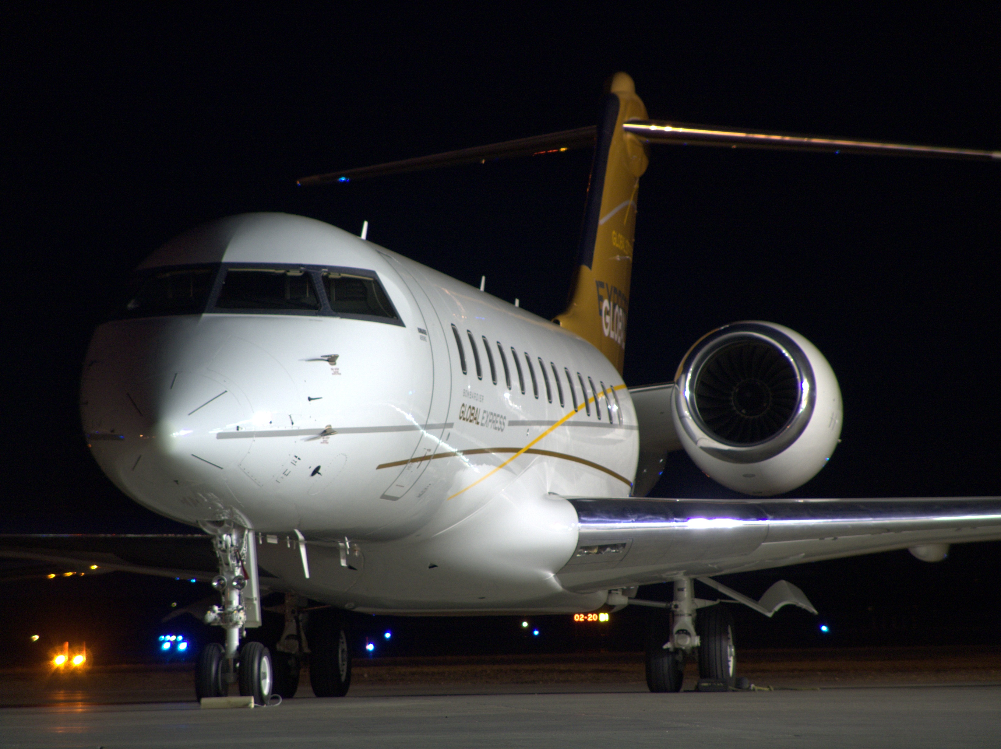 Global Express private jet parked on an airport tarmac at night