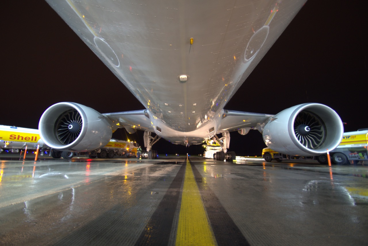 Commercial aircraft refuelling on a wet airport tarmac at night