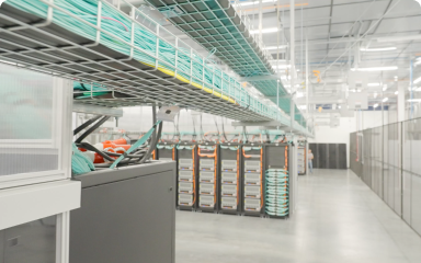 Modern data center aisle with server racks and overhead cable management trays.