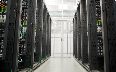 A bright, clean data center aisle with rows of black server racks on both sides.