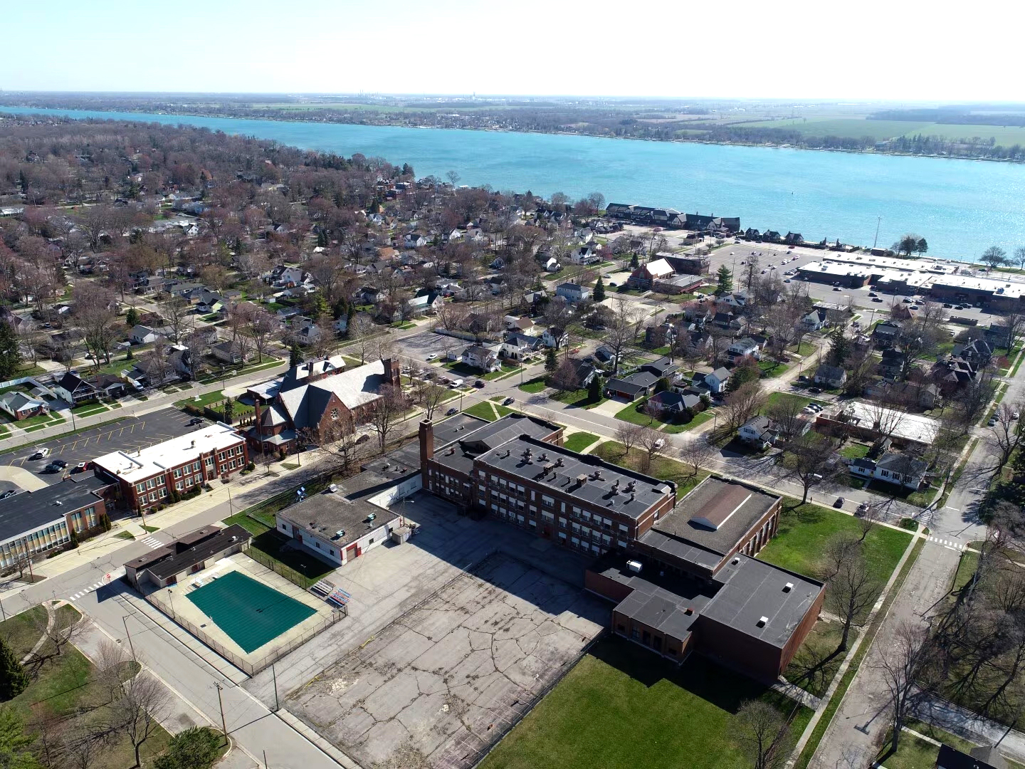 Aerial view of a small town with a school complex, residential houses, and a river in the background.