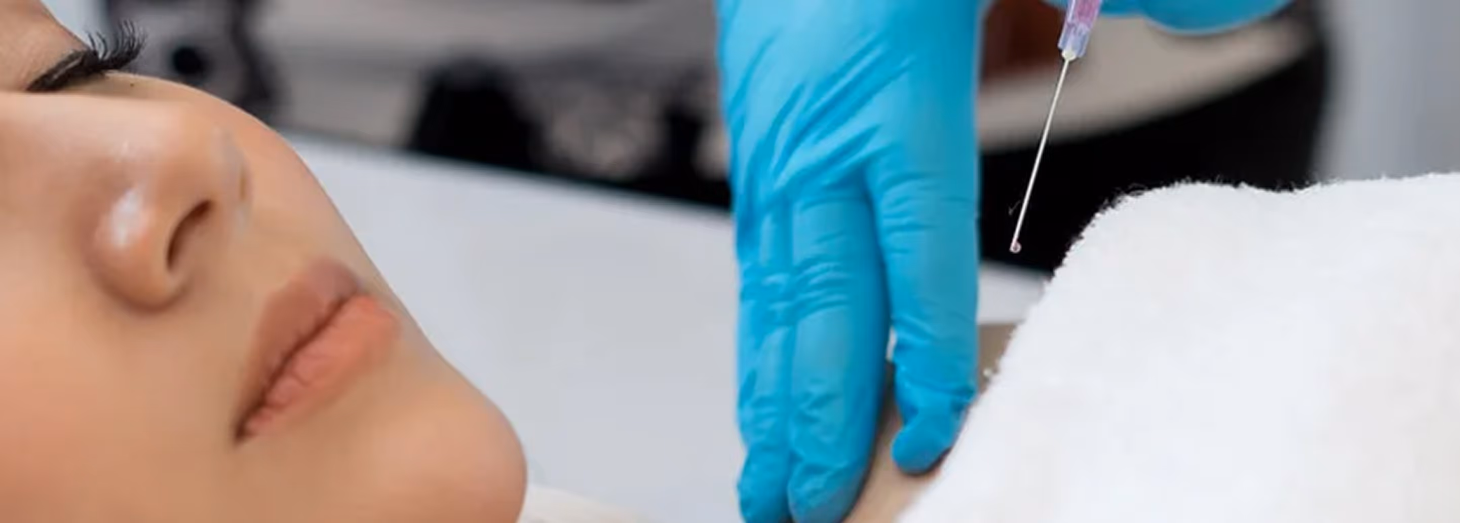 Close-up of a person receiving an injection in the shoulder from a gloved hand with a syringe.