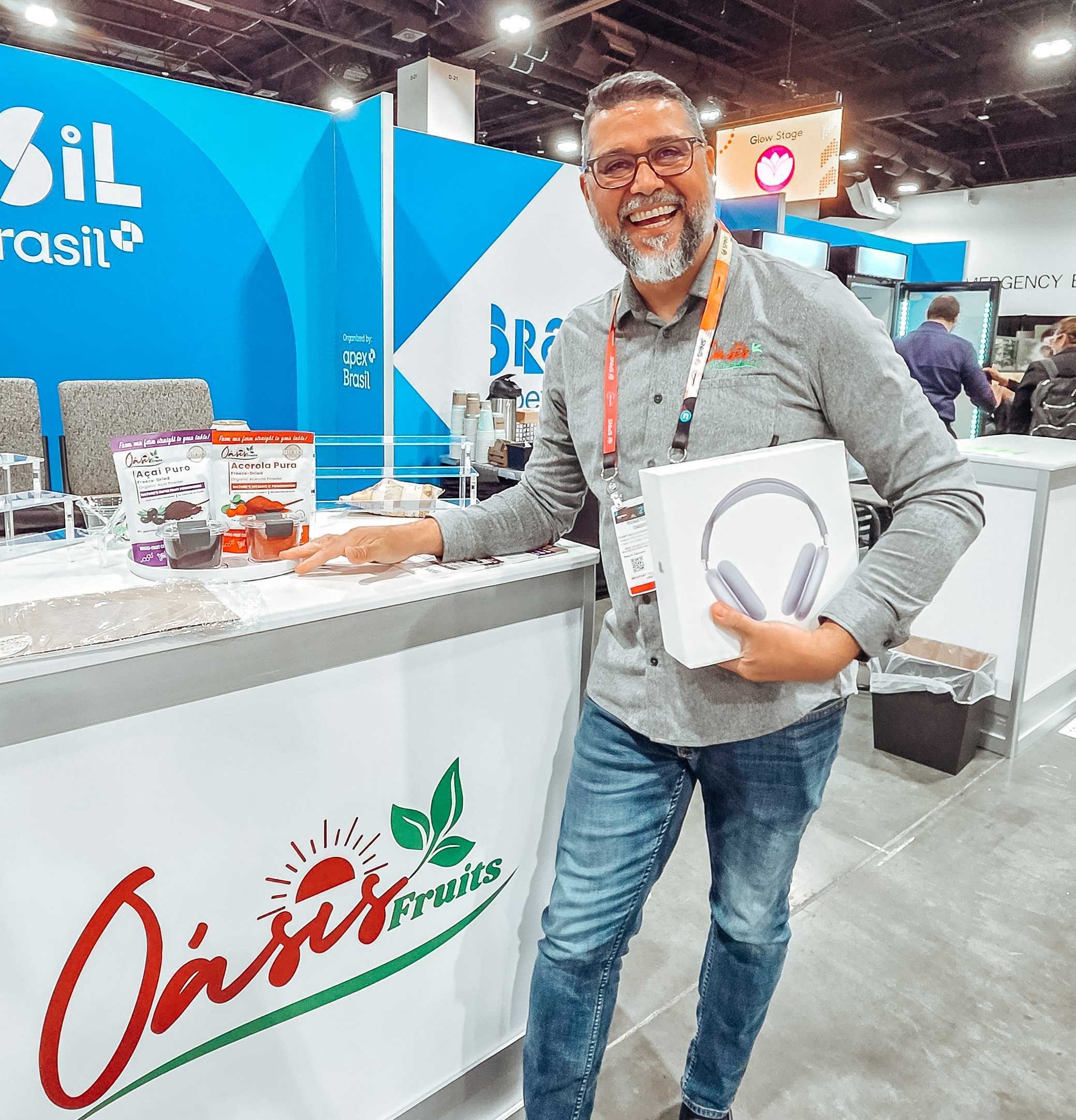 Renato from Oásis Fruits holding his AirPods Max prize at the Verai booth during Newtopia Now
