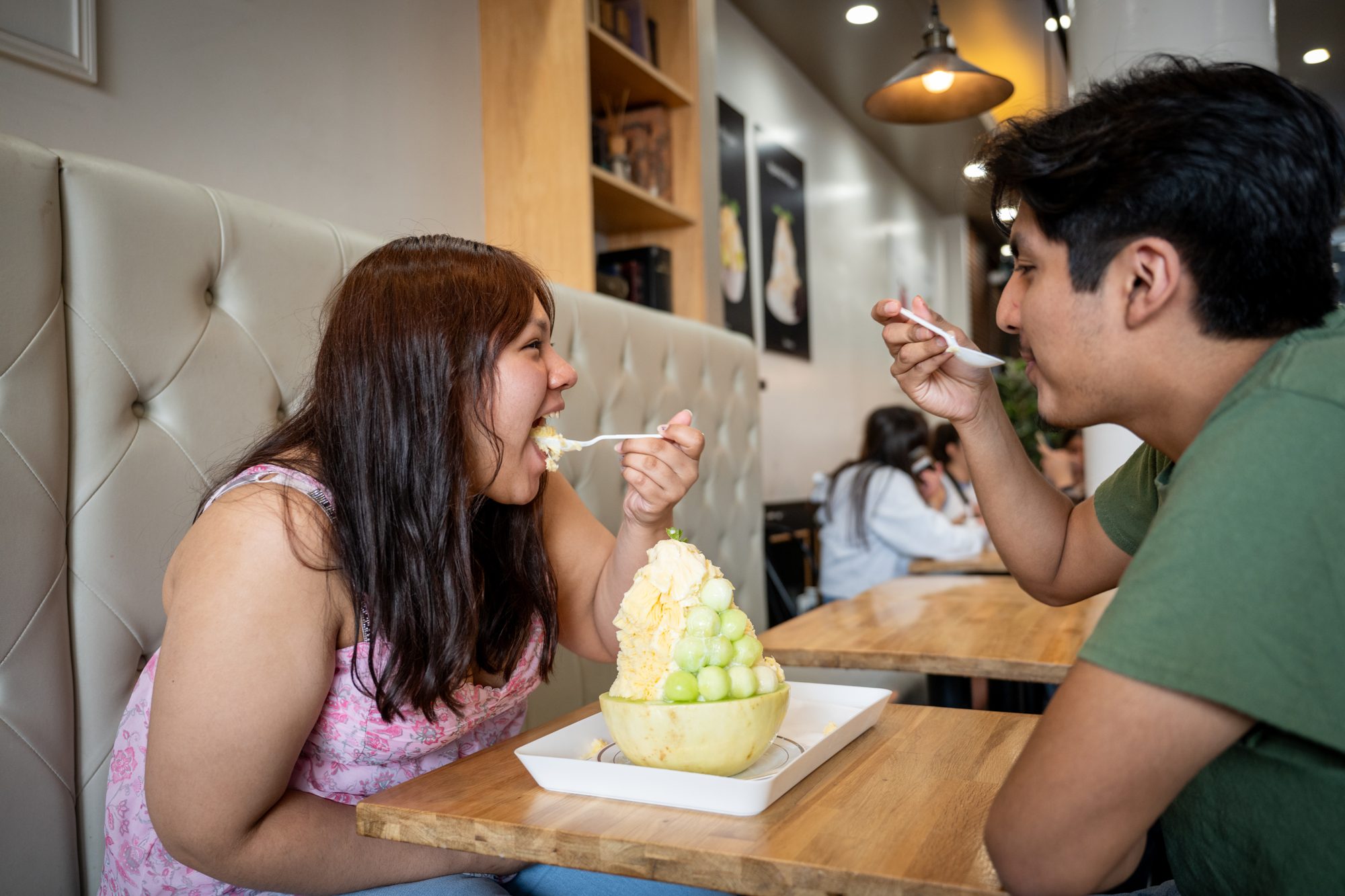 Two customers sharing a bingsu bowl at a table inside an Oakobing cafe