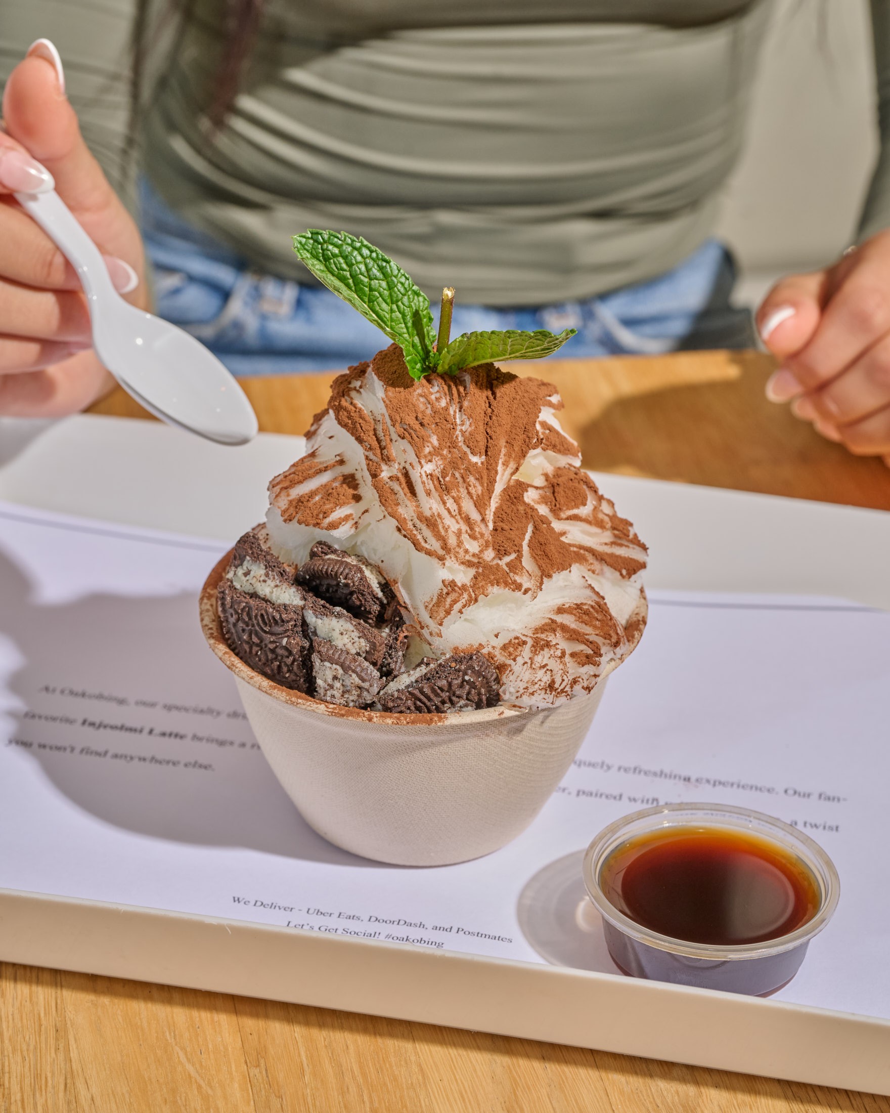 An americano served alongside an Oreo tiramisu bingsu bowl on a cafe table
