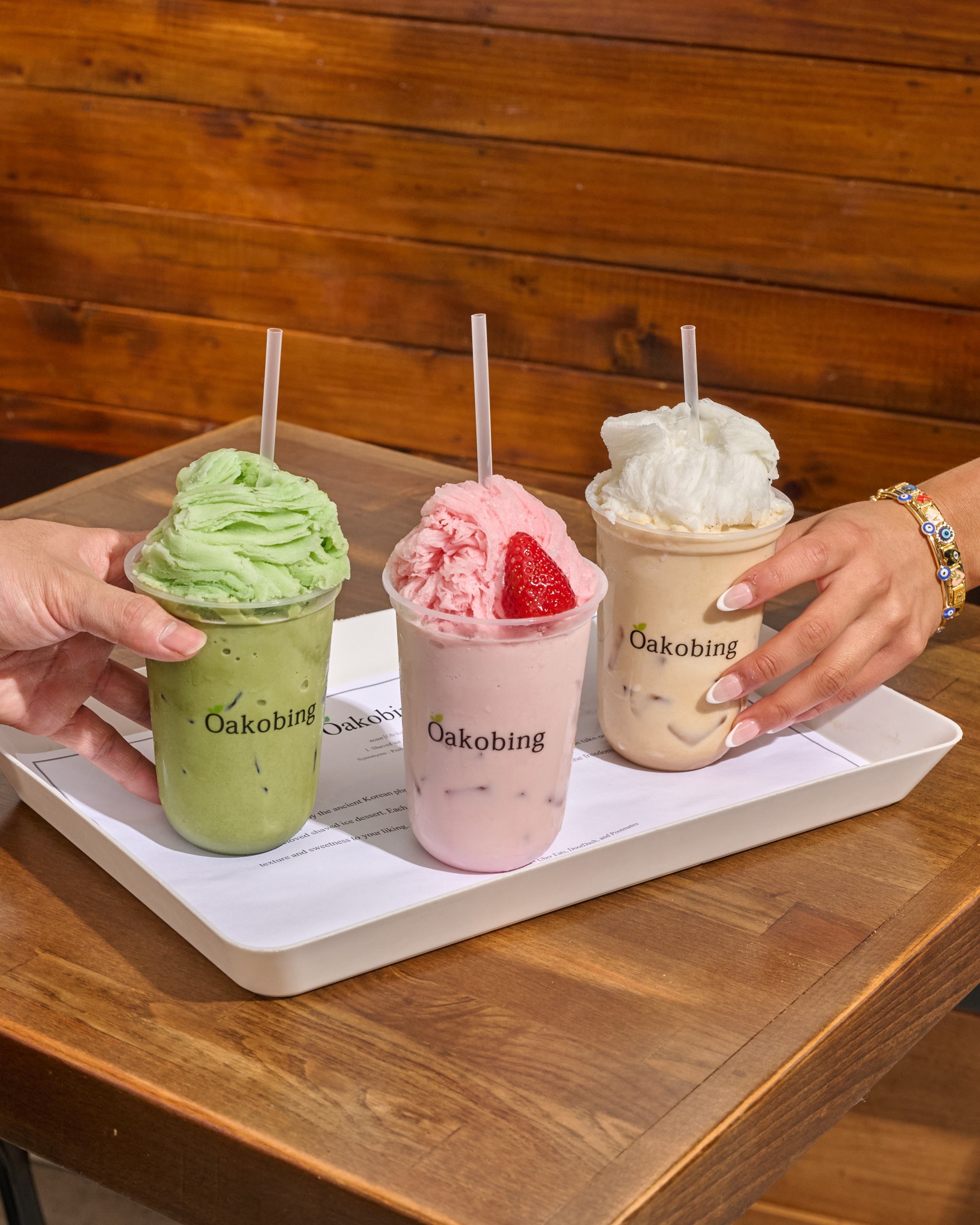 Three Oakobing drinks - green tea, strawberry and injeolmi - on a tray in the Koreatown store