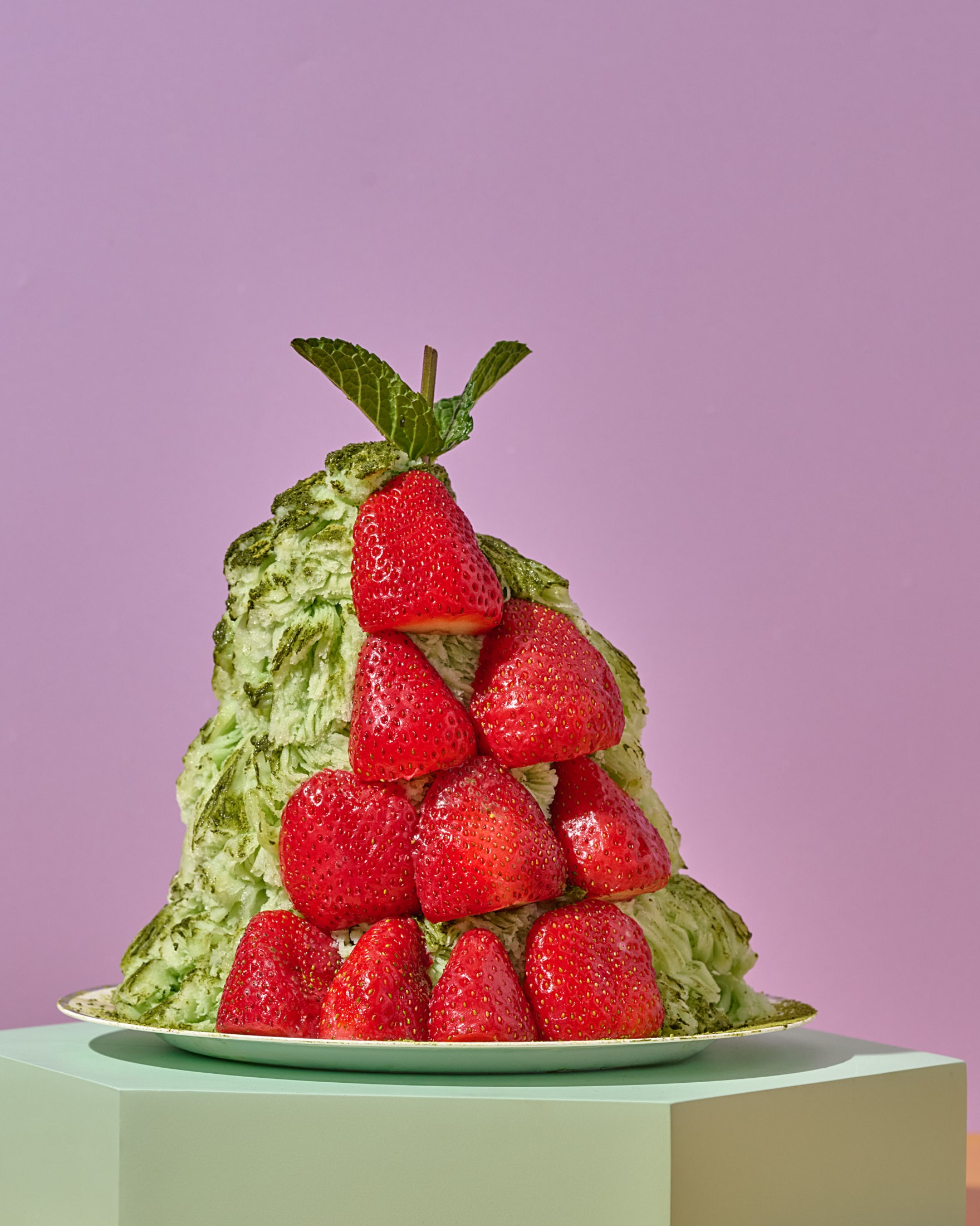 Green tea bingsu stacked with whole strawberries, a modern Korean shaved ice flavor