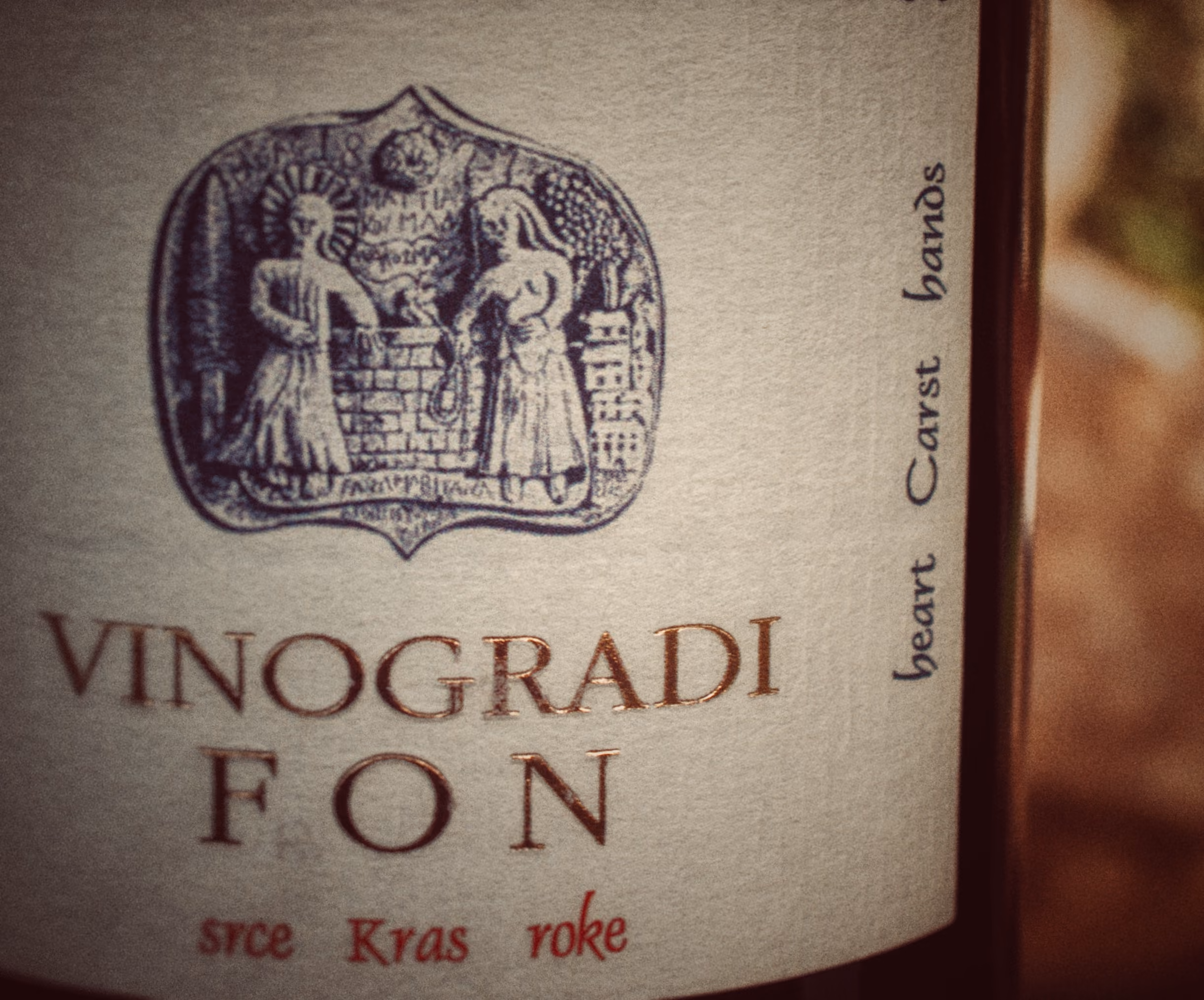Wine label 'Vinogradi Fon' with an emblem showing two figures by a brick wall and text 'heart Carst hands'.