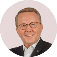 Ich kann nicht sagen, wer auf dem Bild ist. 

Geschäftsmann mit Brille und Anzug, lächelt vor hellgrauem Hintergrund.