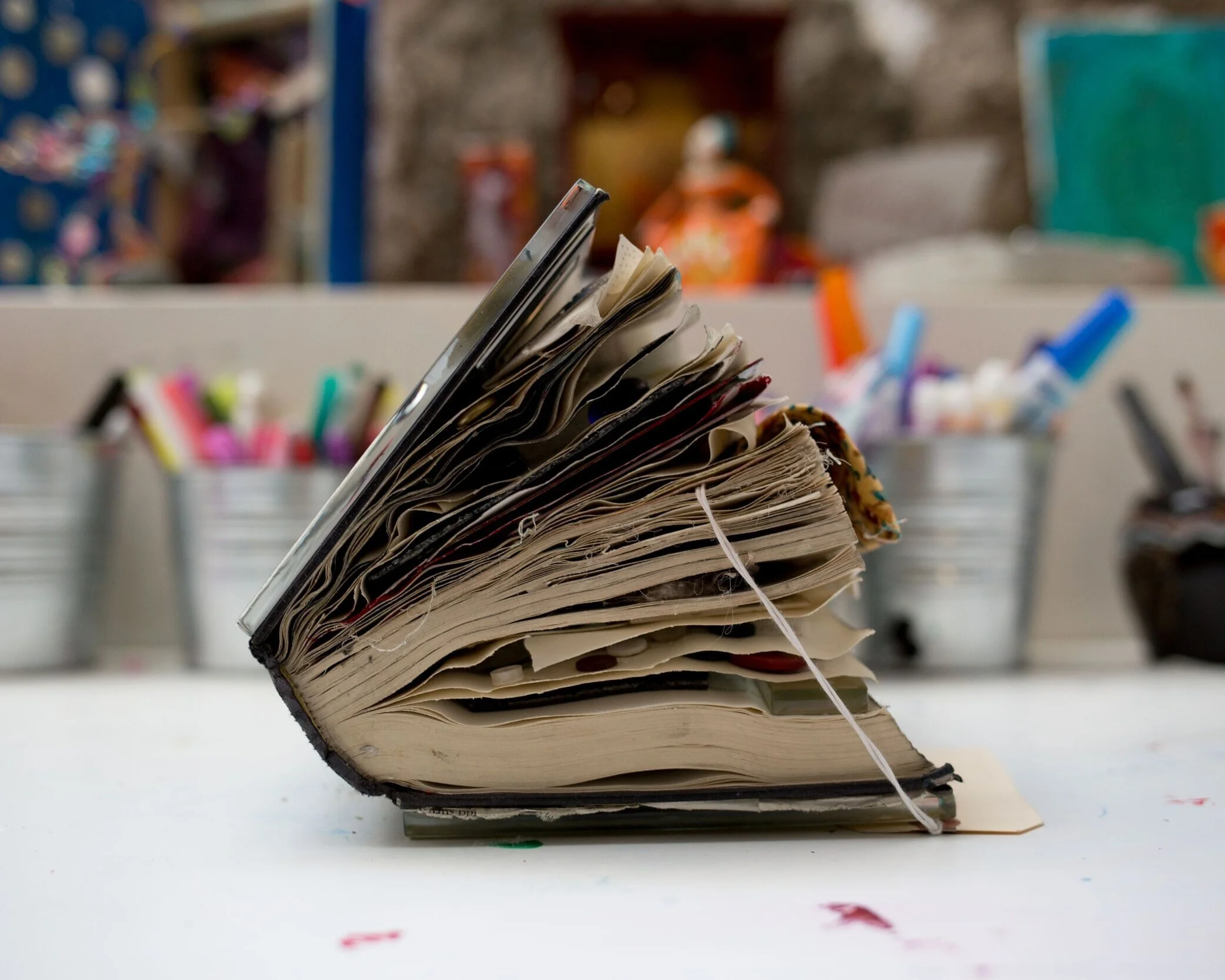 Side view of an old, thick book with worn, creased pages and a string tied around it.