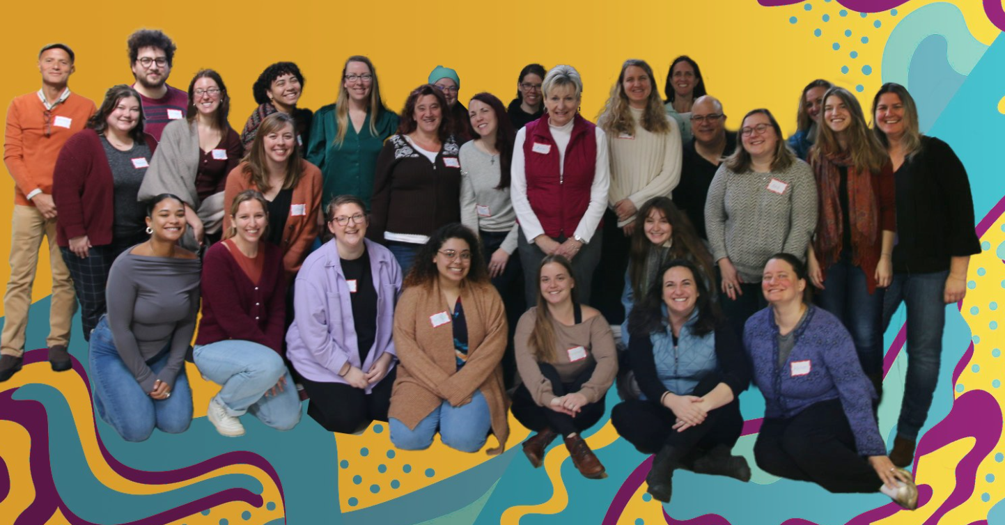 Group photo of 26 people smiling, posed in two rows against a colorful abstract background.
