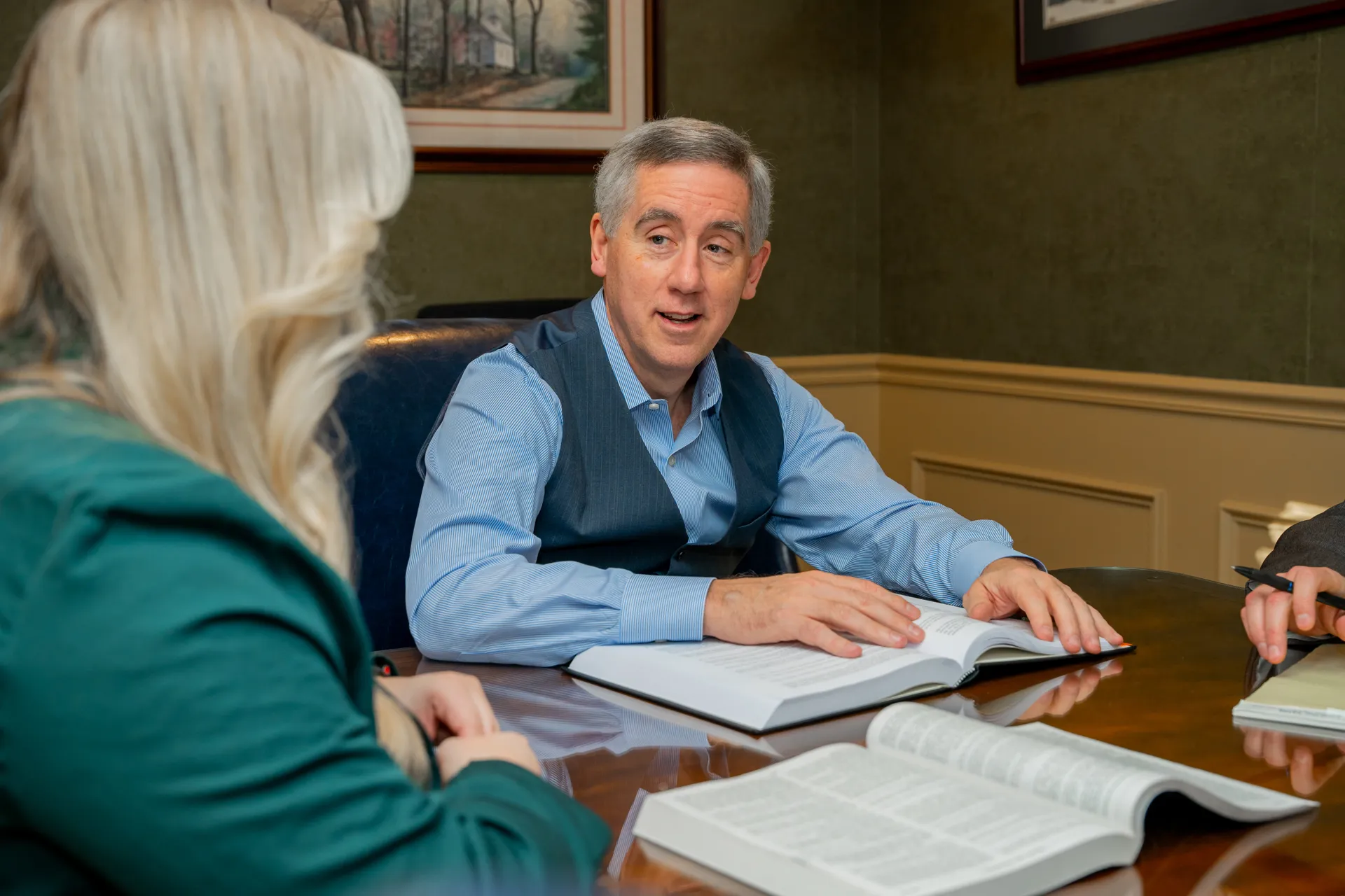 Attorney Dail Cantrell talking to woman across a table with open books in an office setting.
