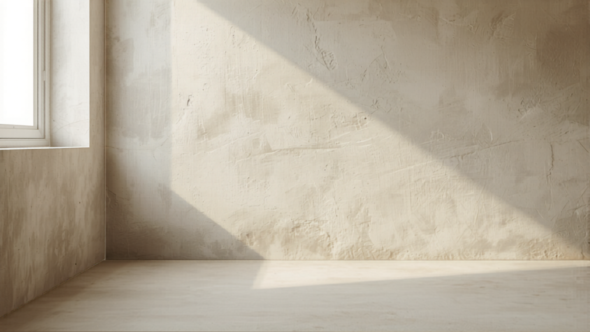 Quiet corner of a minimal studio workspace, plaster wall meeting concrete floor in diffuse natural light