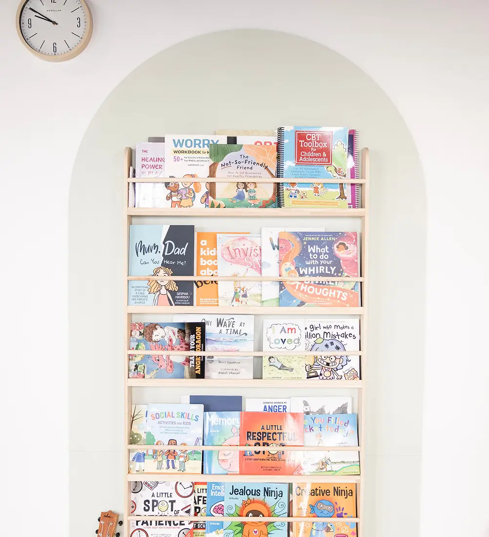 Arched bookshelf in our child therapy office stocked with social-emotional and CBT workbooks for kids