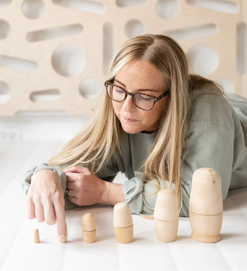 Play therapist using wooden nesting dolls in a one-on-one play therapy session at Playful Pathways