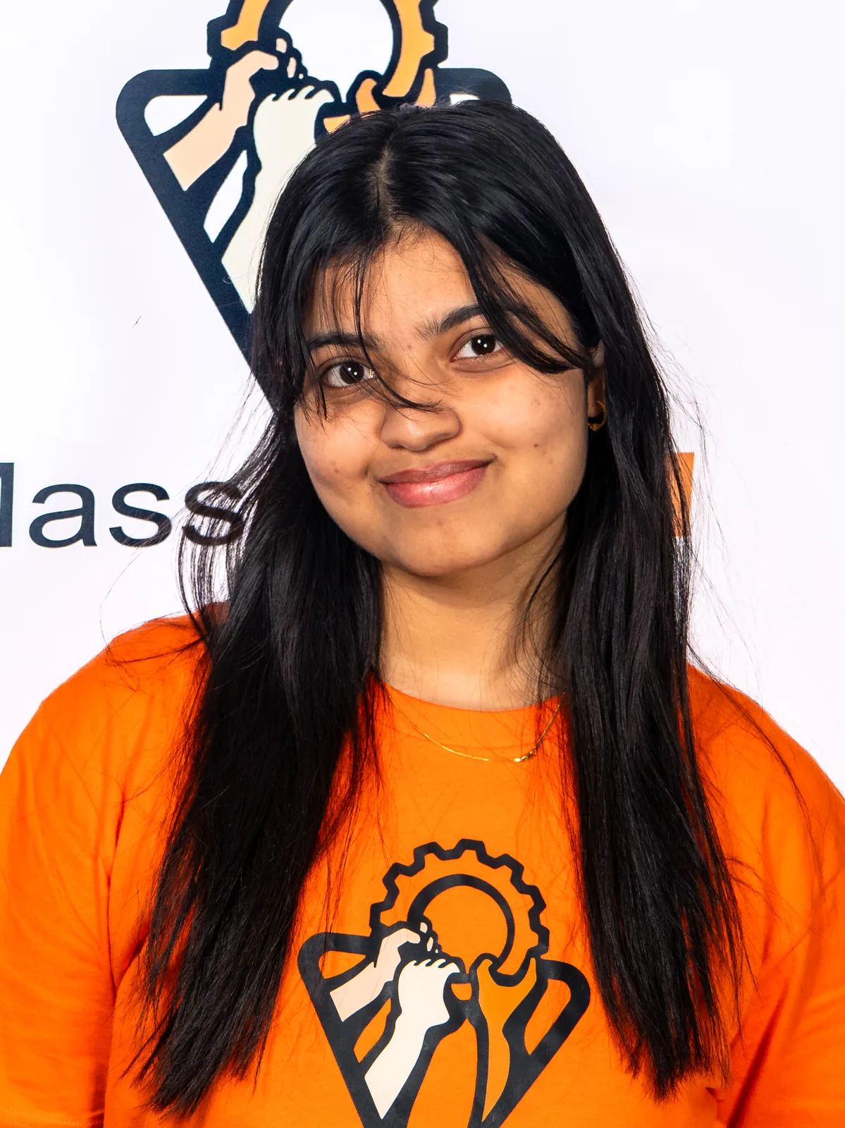 Headshot of Apurba Fatima, smiling and wearing an orange MassCOSH shirt.