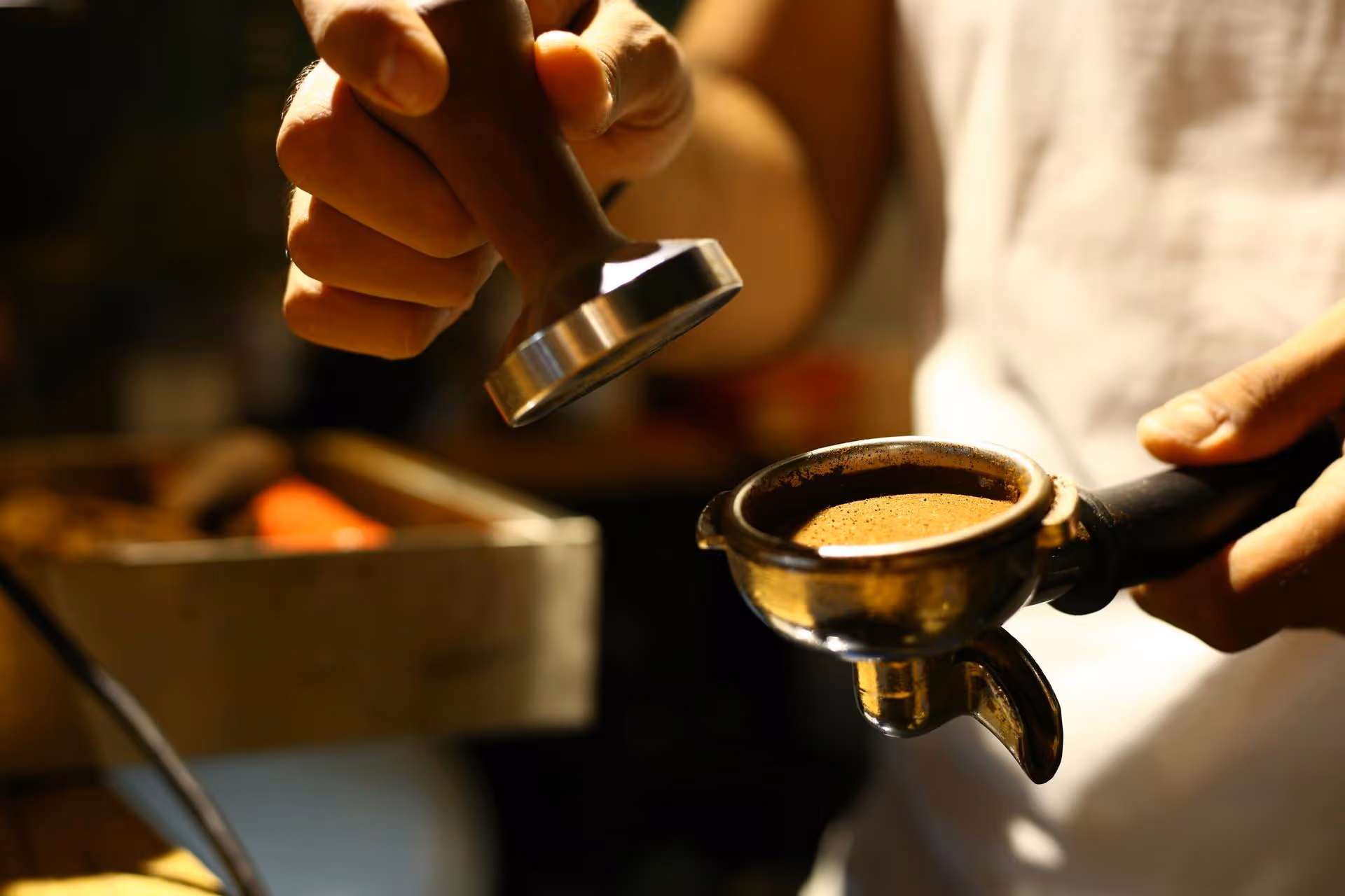 Hand tamping ground coffee in a portafilter for espresso preparation.